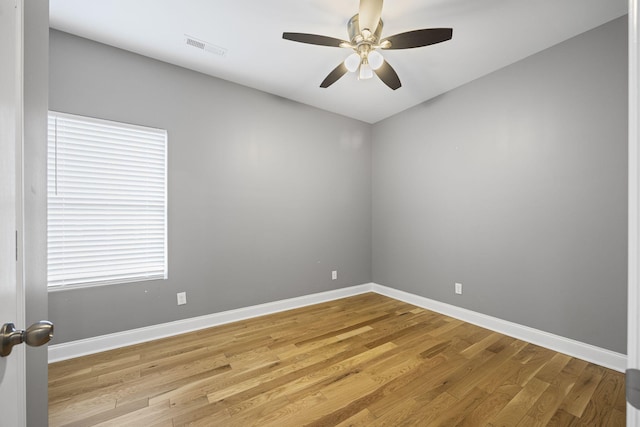 empty room with baseboards, a ceiling fan, and light wood finished floors