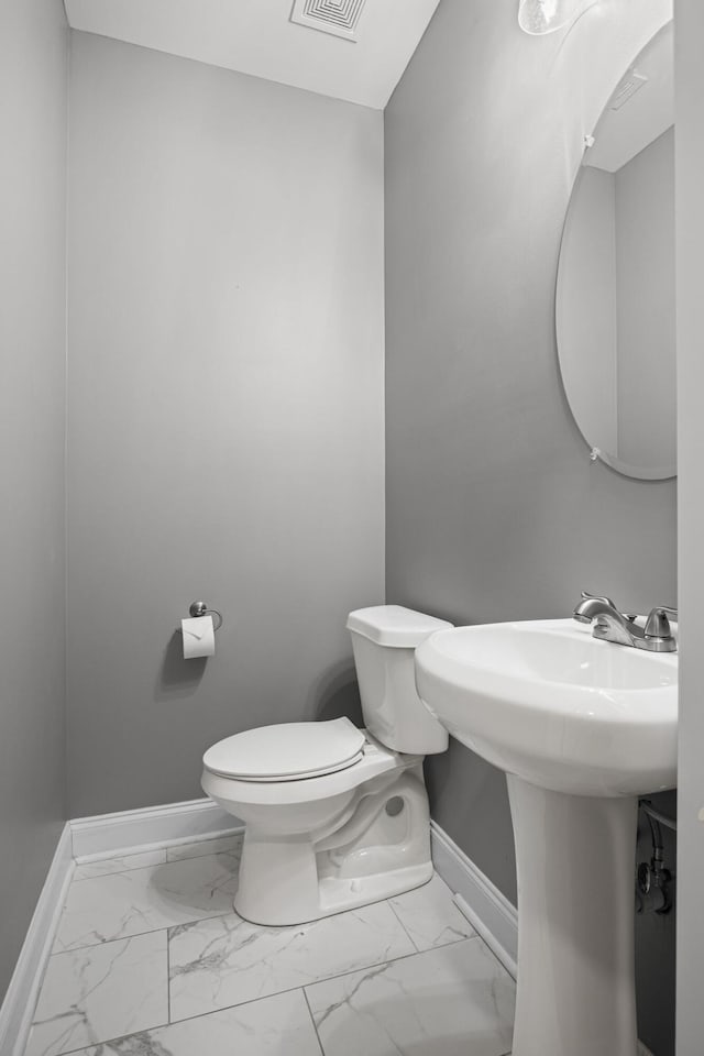 bathroom featuring toilet, baseboards, and marble finish floor