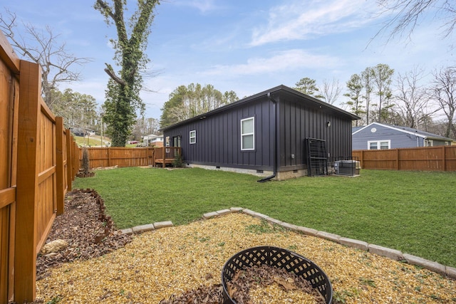 back of house featuring a yard, central AC unit, board and batten siding, and a fenced backyard