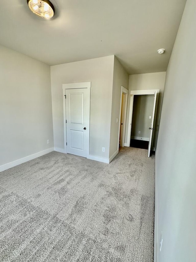 unfurnished bedroom featuring baseboards and light carpet