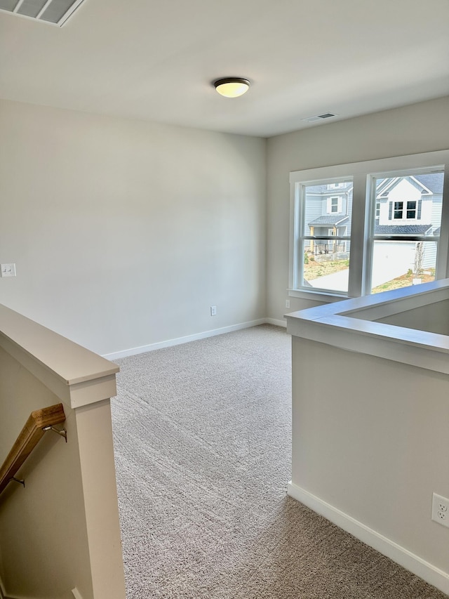 empty room featuring light carpet, visible vents, and baseboards