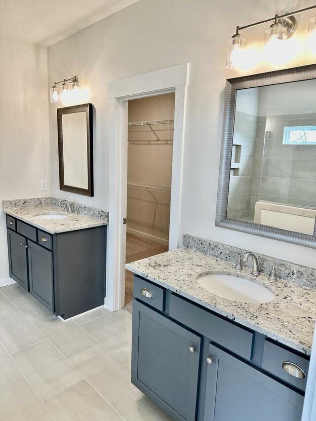 full bath with a sink, two vanities, a spacious closet, and tile patterned floors