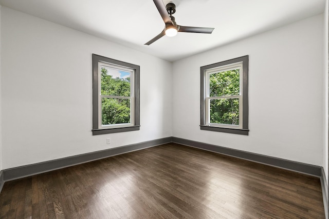 empty room featuring dark wood-style flooring, a healthy amount of sunlight, ceiling fan, and baseboards