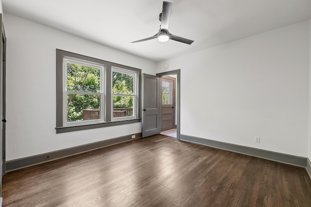 spare room with dark wood finished floors, baseboards, and ceiling fan