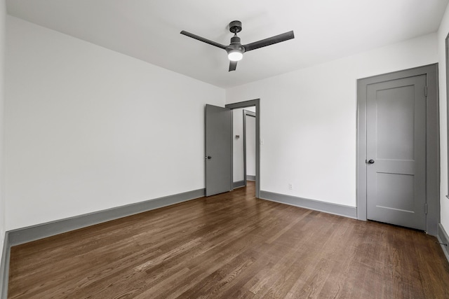 unfurnished bedroom featuring ceiling fan, baseboards, and dark wood finished floors