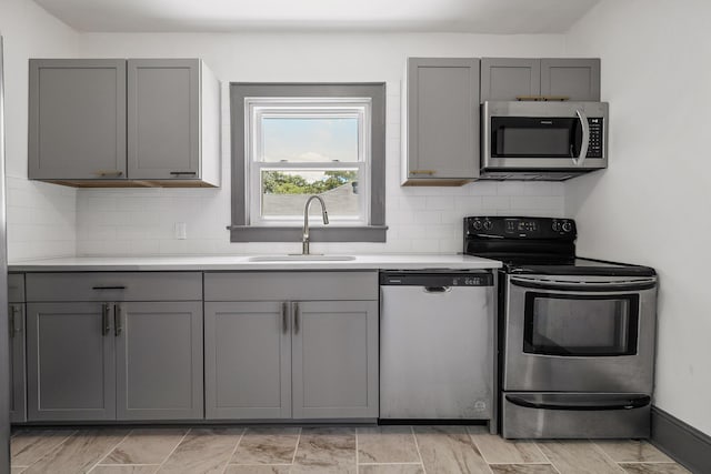 kitchen featuring a sink, stainless steel appliances, tasteful backsplash, and gray cabinets