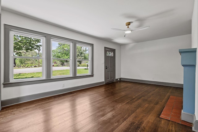 interior space featuring dark wood-style floors, baseboards, visible vents, and ceiling fan