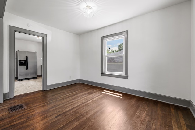 spare room featuring visible vents, baseboards, and wood finished floors