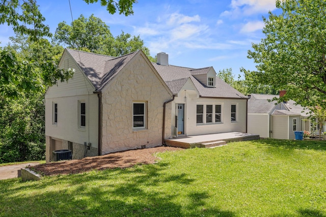 exterior space featuring a patio, a chimney, a shingled roof, stone siding, and a front lawn