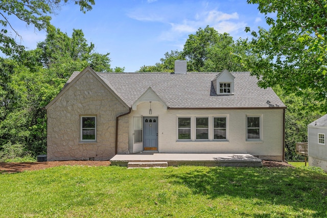 view of front of house featuring stone siding, a chimney, a front lawn, and roof with shingles