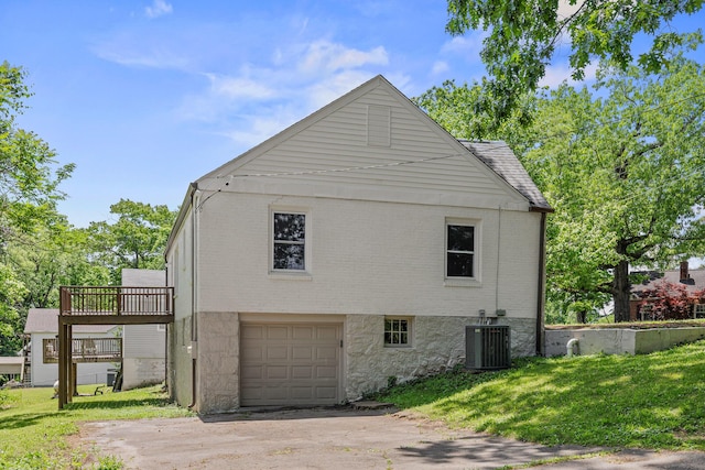 view of property exterior featuring driveway, an attached garage, a yard, central air condition unit, and brick siding