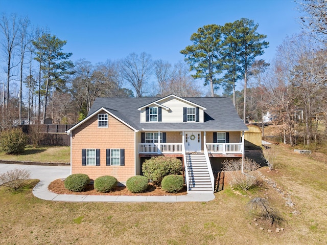 view of front of house featuring aphalt driveway, covered porch, stairway, and a front lawn