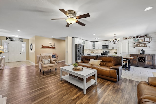 living room with light wood-style floors, recessed lighting, and ceiling fan with notable chandelier