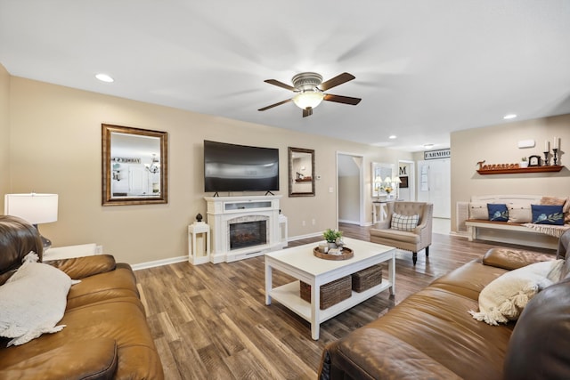 living room with baseboards, a fireplace with raised hearth, wood finished floors, and recessed lighting