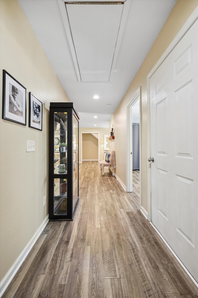 hallway with attic access, baseboards, wood finished floors, and recessed lighting