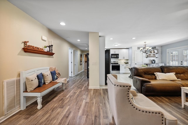 living room with recessed lighting, wood finished floors, visible vents, baseboards, and an inviting chandelier