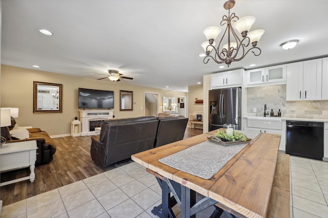 dining area with light tile patterned floors, recessed lighting, a fireplace, and ceiling fan with notable chandelier