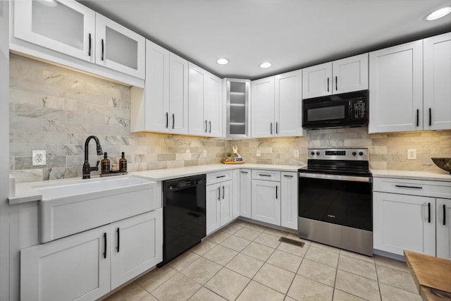 kitchen with light tile patterned floors, black appliances, light countertops, and decorative backsplash