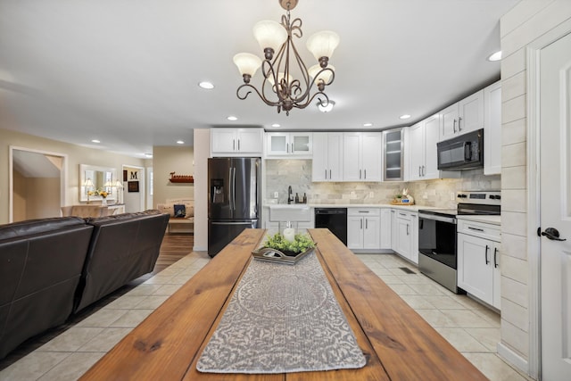 kitchen featuring wooden counters, backsplash, glass insert cabinets, light tile patterned flooring, and black appliances