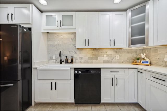 kitchen featuring a sink, white cabinets, black dishwasher, light countertops, and freestanding refrigerator