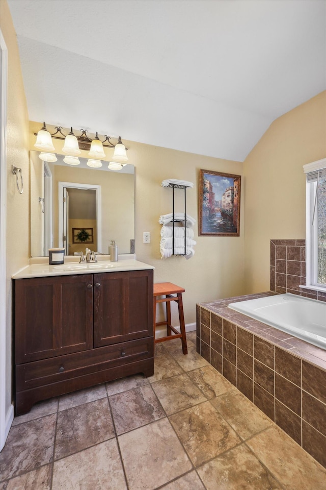 full bathroom featuring vaulted ceiling, vanity, and a bath