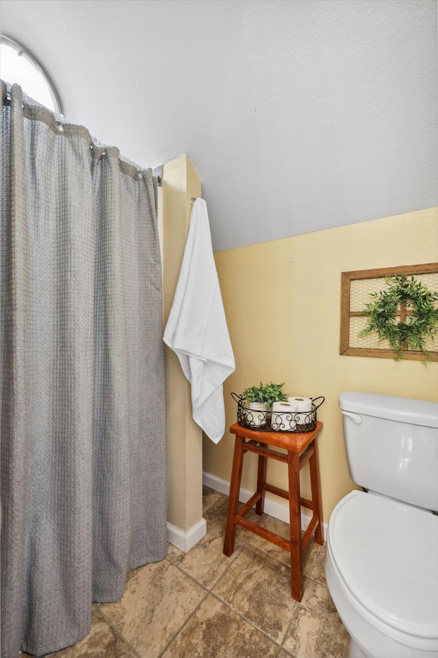 bathroom with toilet, baseboards, and a shower with shower curtain