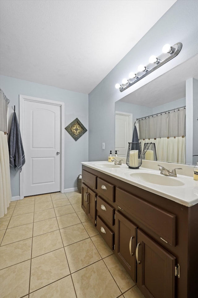 bathroom featuring toilet, double vanity, a sink, and tile patterned floors