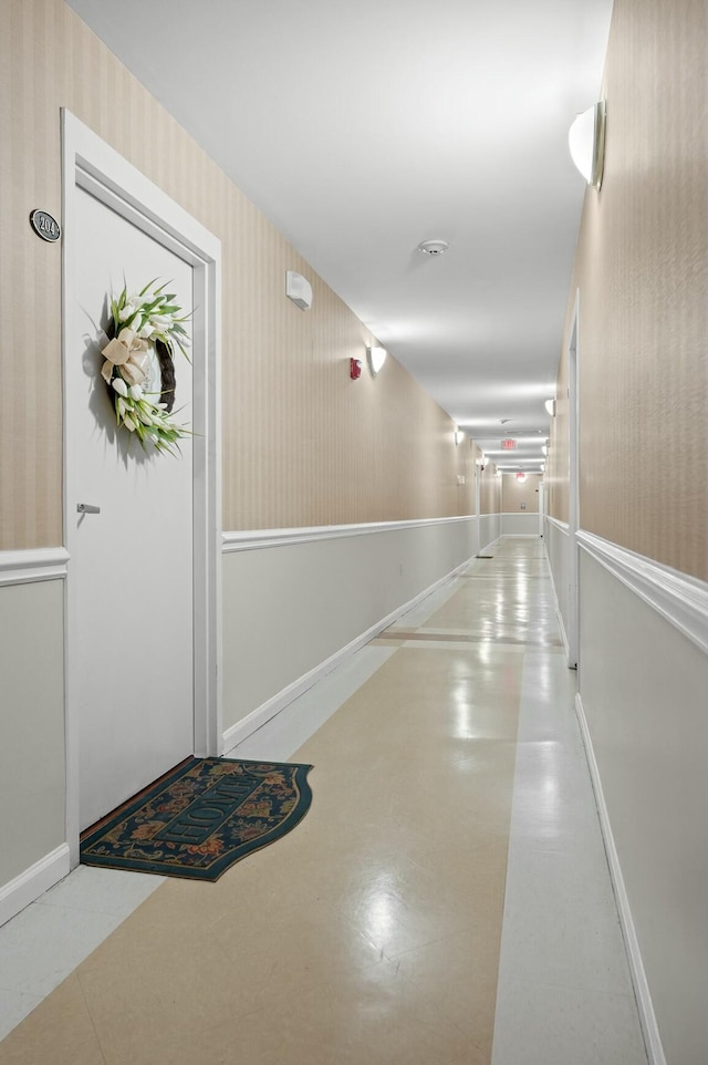 corridor featuring baseboards and wallpapered walls