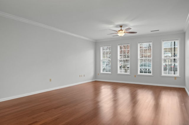 spare room featuring baseboards, visible vents, ceiling fan, ornamental molding, and wood finished floors