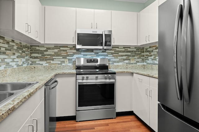 kitchen featuring light wood-style floors, white cabinetry, appliances with stainless steel finishes, and backsplash