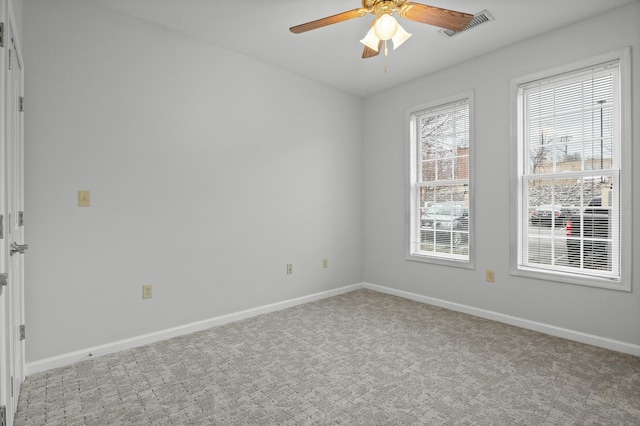 carpeted spare room featuring baseboards, visible vents, and a ceiling fan