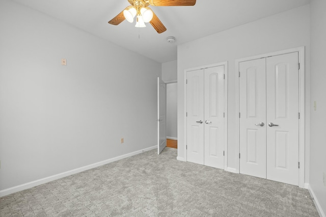 unfurnished bedroom with multiple closets, carpet floors, baseboards, and a ceiling fan