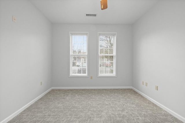 carpeted empty room with visible vents, ceiling fan, and baseboards