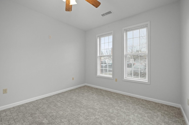 carpeted spare room featuring a ceiling fan, visible vents, and baseboards