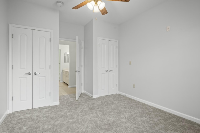 unfurnished bedroom with multiple closets, light carpet, baseboards, and a ceiling fan