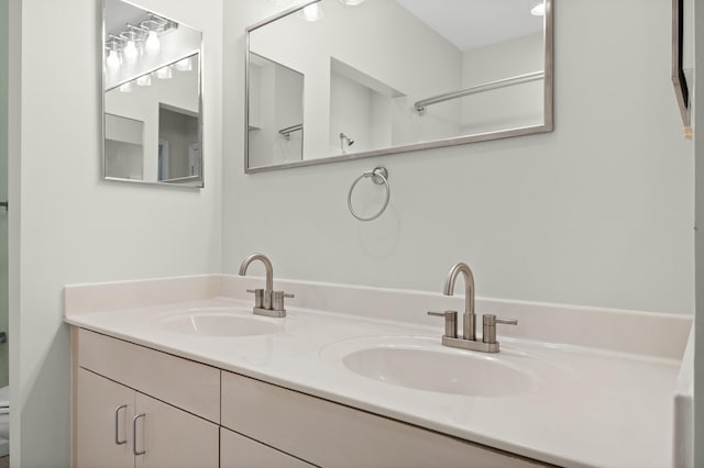 bathroom with a sink, toilet, and double vanity