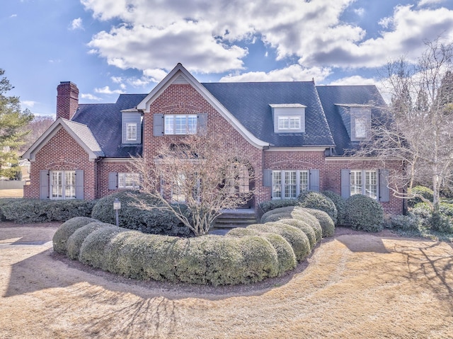 view of front of house with brick siding, a chimney, and french doors