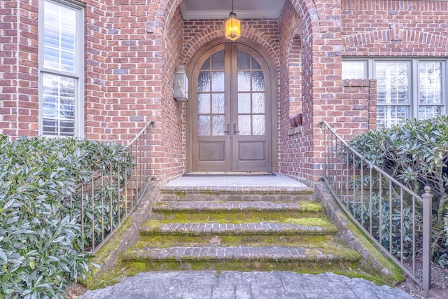 view of exterior entry featuring brick siding and french doors