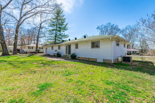 rear view of house with cooling unit, entry steps, a yard, and fence