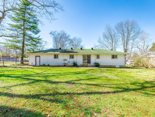 rear view of property with fence and a lawn