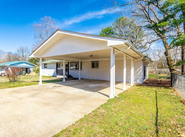 back of house with an attached carport, concrete driveway, a yard, and fence