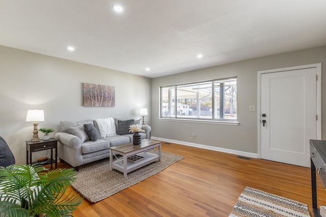 living area with recessed lighting, visible vents, baseboards, and light wood finished floors