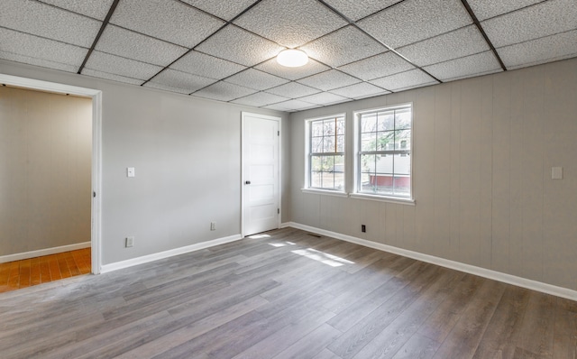 spare room with wood finished floors, baseboards, and a paneled ceiling