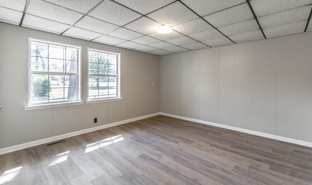 spare room with visible vents, a paneled ceiling, baseboards, and wood finished floors