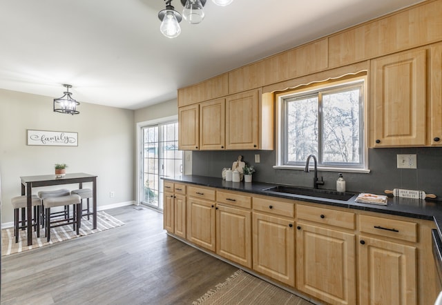 kitchen featuring a chandelier, dark countertops, light brown cabinetry, and a sink