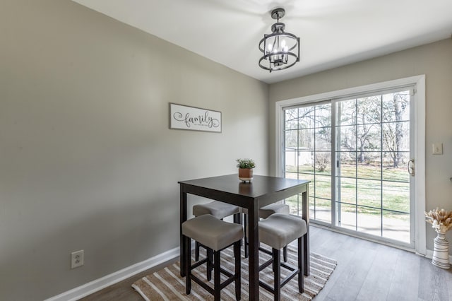 dining area with a wealth of natural light, a notable chandelier, and wood finished floors