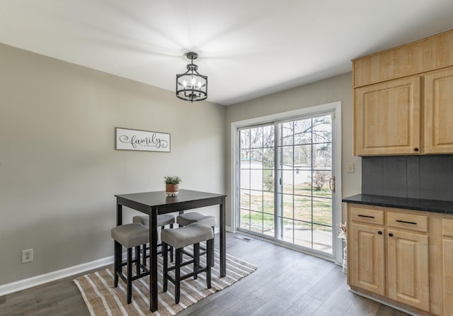 dining room featuring dark wood-type flooring, a notable chandelier, visible vents, and baseboards