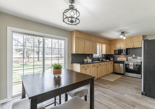 kitchen featuring light brown cabinets, appliances with stainless steel finishes, light wood-type flooring, and dark countertops