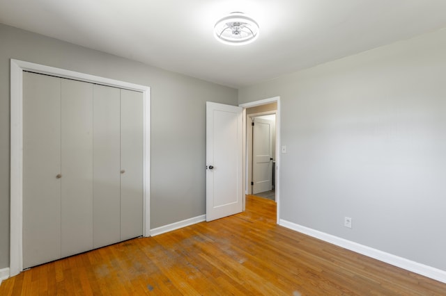 unfurnished bedroom with a closet, baseboards, and wood-type flooring