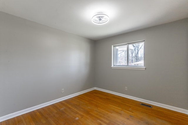 spare room with visible vents, baseboards, and hardwood / wood-style floors